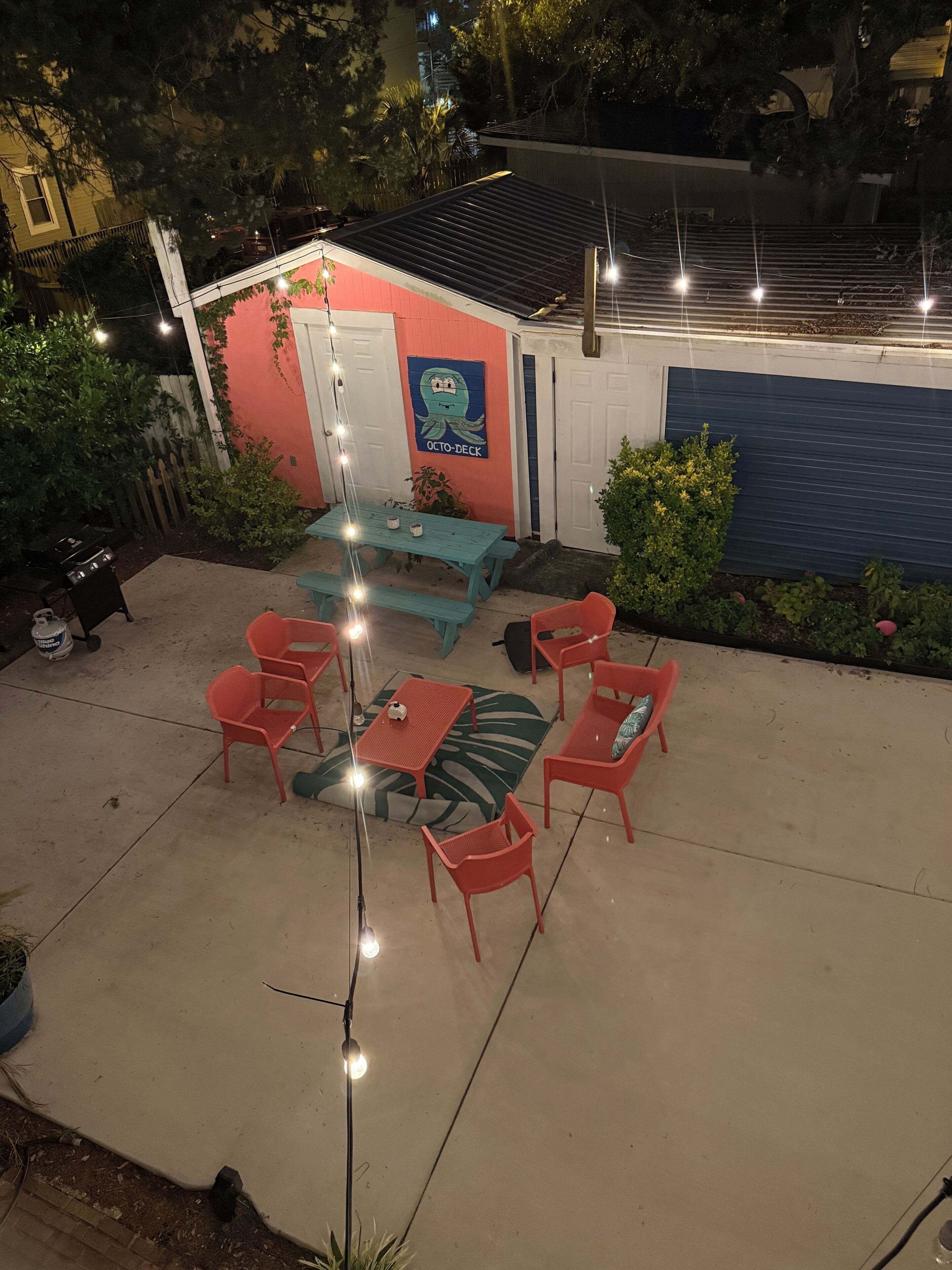 A patio with a table and chairs, a grill, and a small shed with a mural.