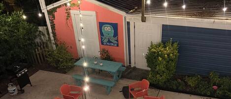 A patio with a table and chairs, a grill, and a small shed with a mural.