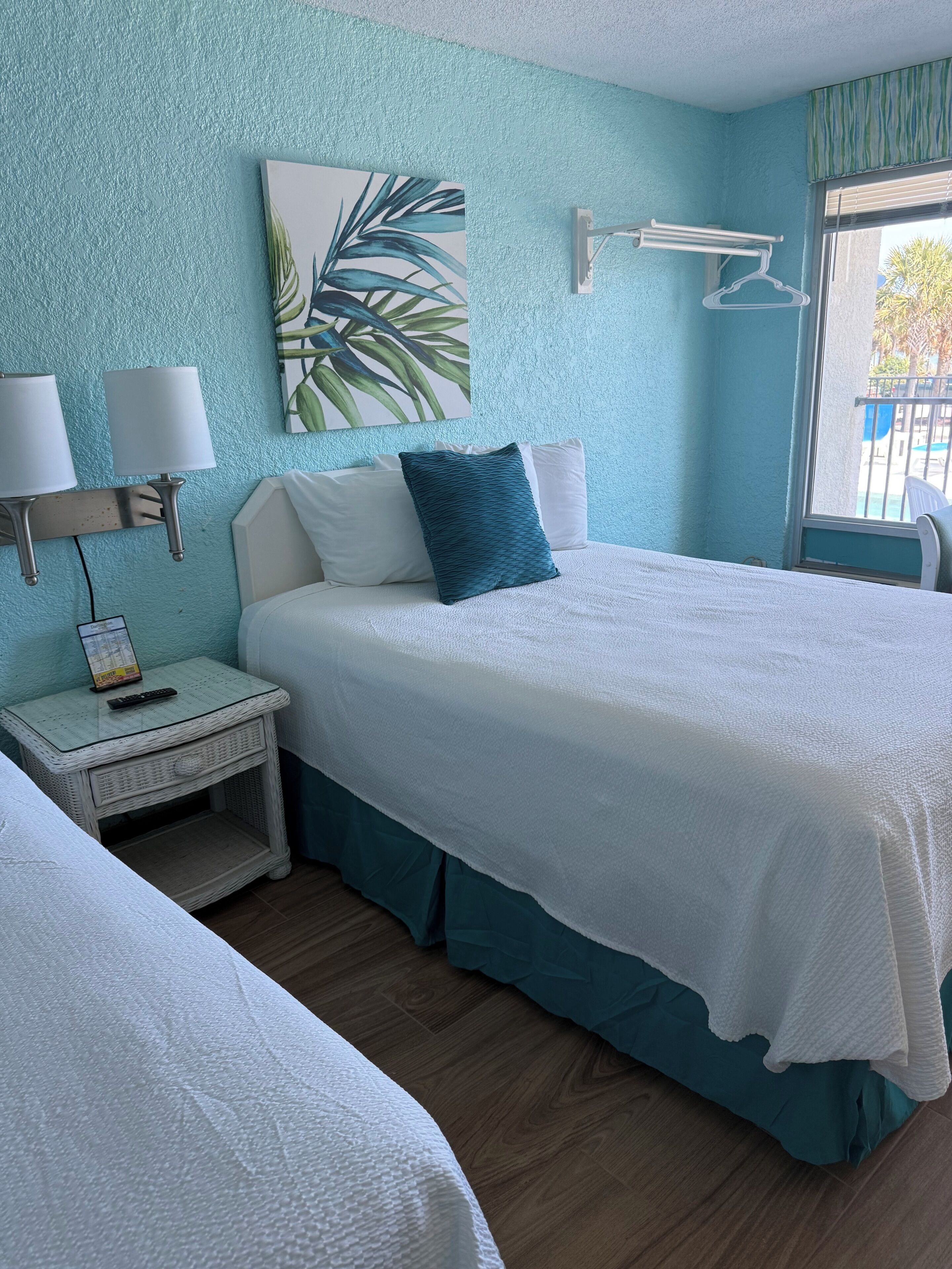 A room with a bed, bedside table, lamp, and a painting on the wall.