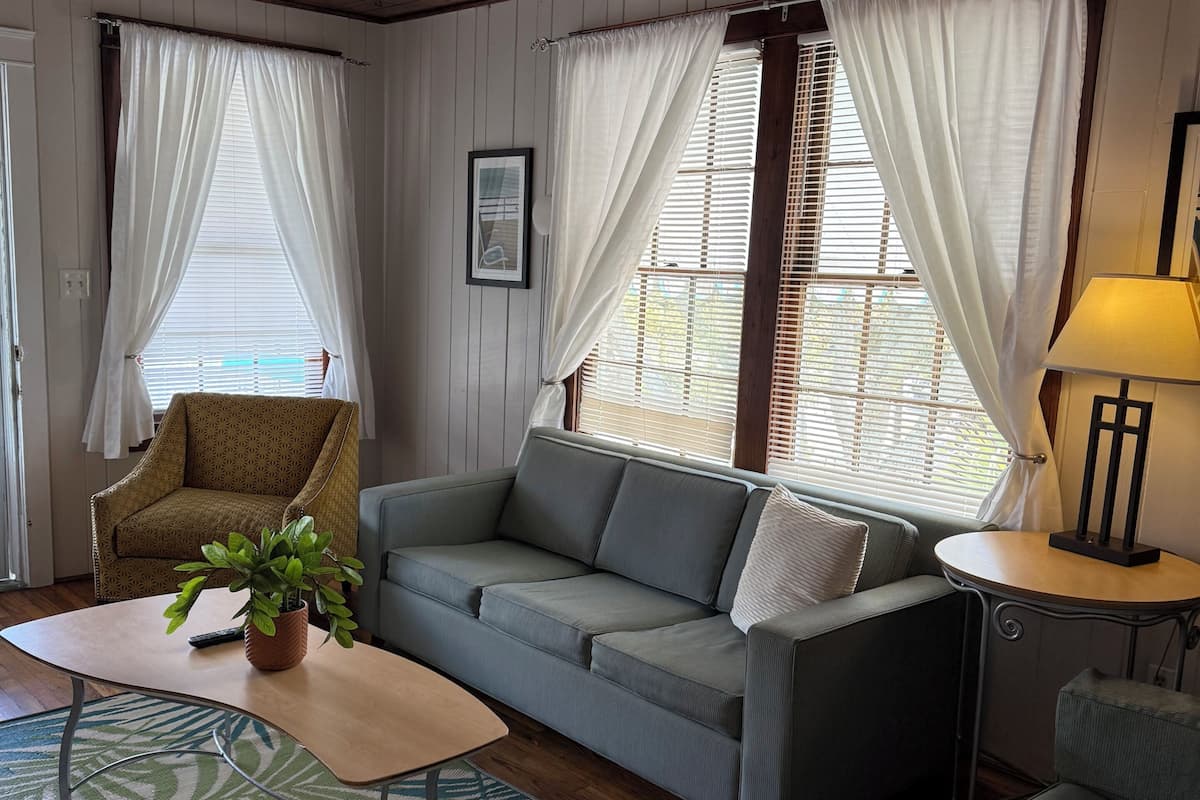 A cozy living room with a sofa, armchair, and a small table with a lamp.
