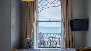 Habitación de hotel con un ventanal grande, un televisor montado en la pared y una cama con cabecero.