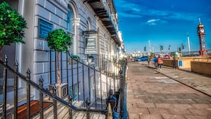 Un edificio junto al agua con una torre de reloj, una escalera y un paseo pavimentado.