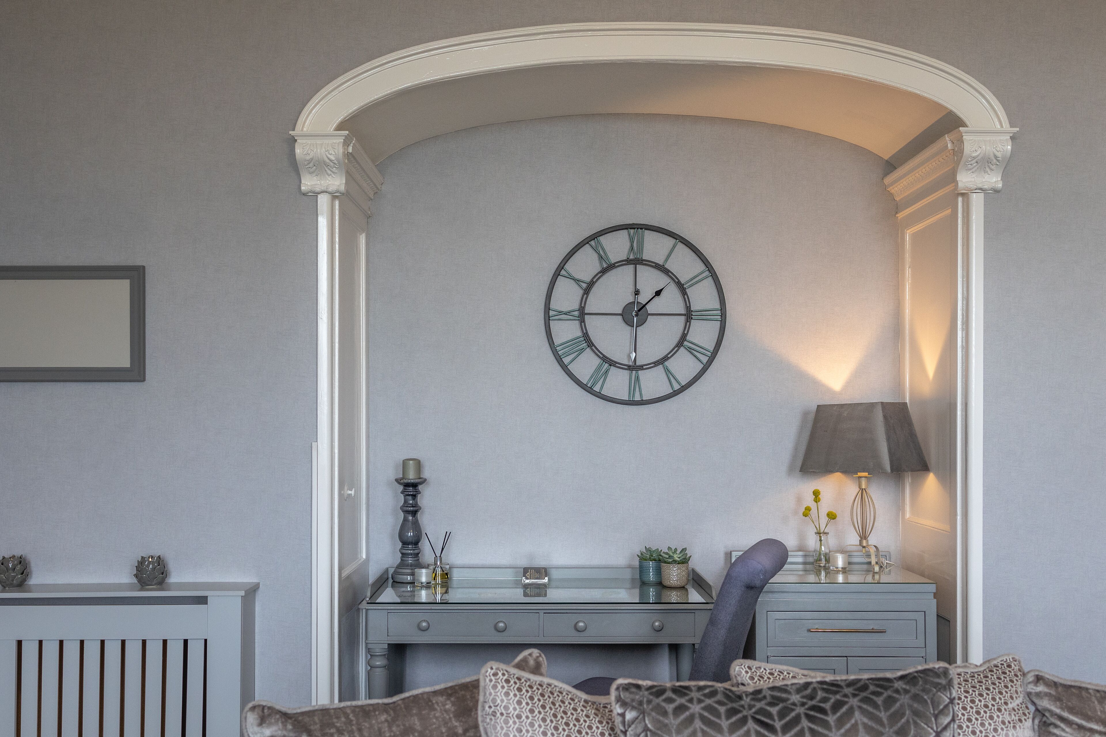 A room with a desk, a clock, and a lamp.