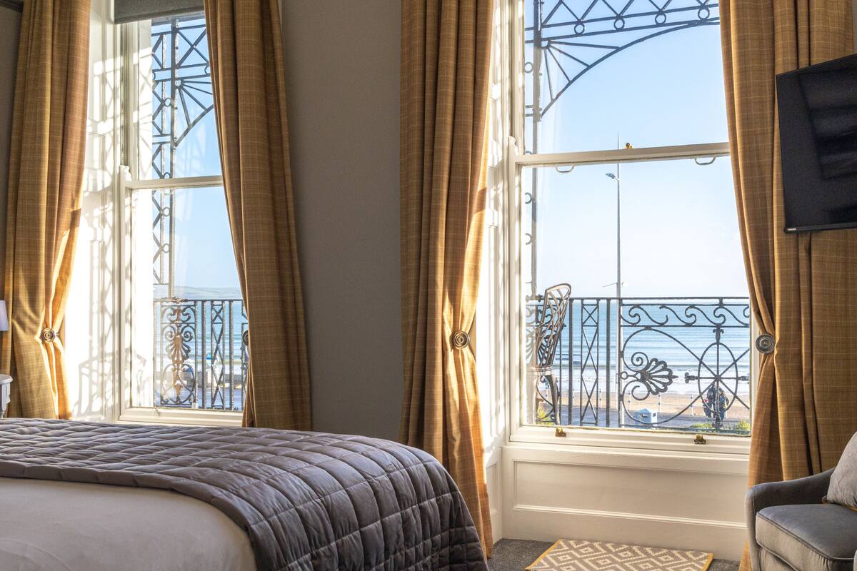 Una habitación de hotel con cama, televisión y balcón con barandilla.