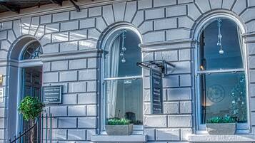 A building with a balcony, a sign for Gloucester House, and a window with a plant.