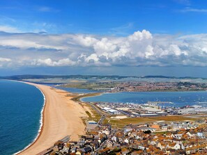 A coastal town with a sandy beach, a marina with boats, and residential buildings. - Gloucester House (Weymouth)