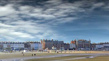 A coastal town with a beach, buildings, and a cloudy sky.