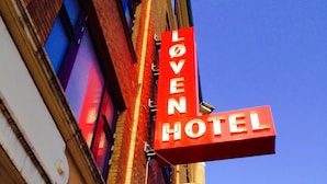 A hotel sign with the name "Loven Hotel" and a smaller sign below it with a lion symbol. - Hotel Loeven (Copenhagen)