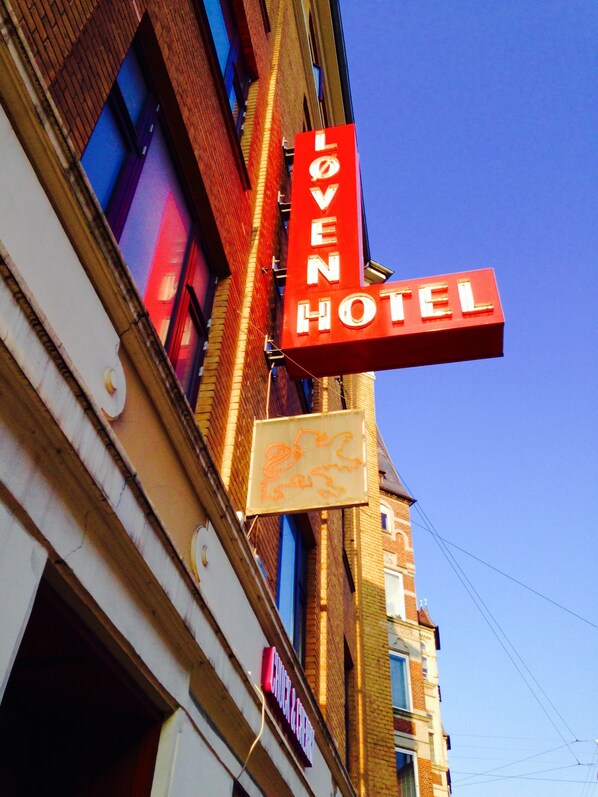 A hotel sign with the name "Loven Hotel" and a smaller sign below it with a lion symbol.