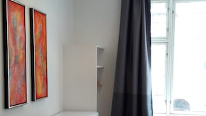 A modern living space with a dining area, a sofa, a window with curtains, and two abstract paintings on the wall. - Hotel Loeven (Copenhagen)