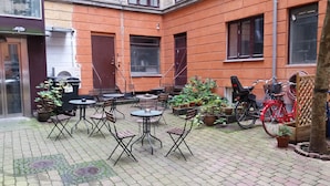 An outdoor seating area with tables and chairs, potted plants, and bicycles. - Hotel Loeven (Copenhagen)