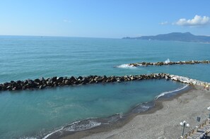 A coastal beach with a rocky breakwater and a clear view of the sea and distant mountains. - Hotel San Pietro (Chiavari)