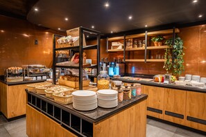 A breakfast buffet with various food items, baskets, and plates. - Hotel Zeezicht Vlieland (Vlieland)