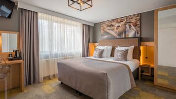 Ein Hotelzimmer mit Bett, Schreibtisch, Fernseher und einem Bild an der Wand.