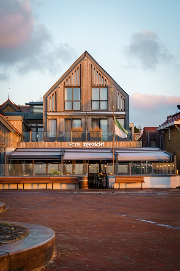 A hotel with a modern design, featuring a prominent signboard and a flag. - Hotel Zeezicht Vlieland (Vlieland)