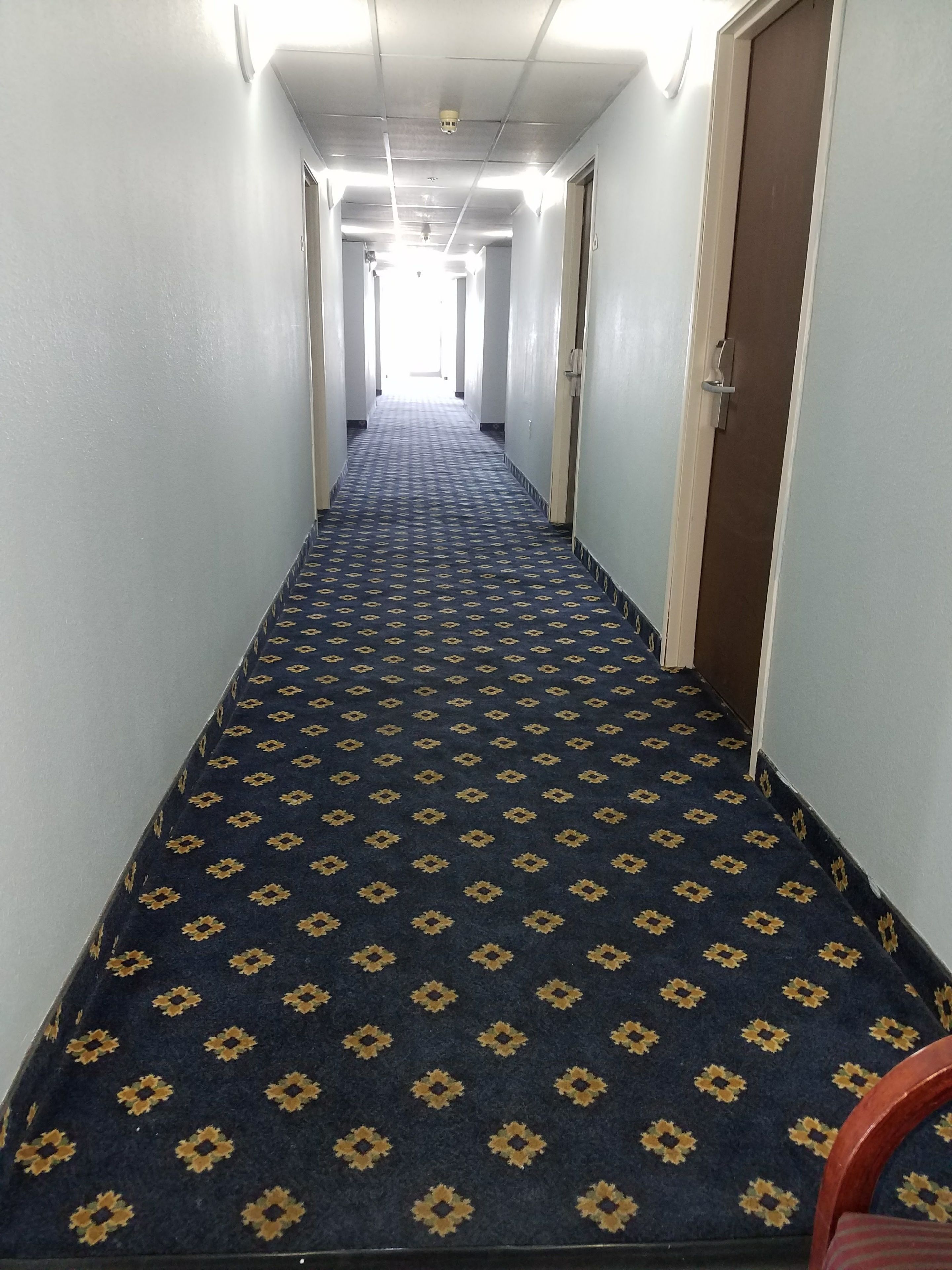 A long, narrow hallway with a patterned carpet and light-colored walls.