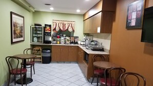 A compact kitchen with a dining area, equipped with a refrigerator, coffee machine, and various kitchen appliances. - Briarwood Inn (Fairfield)