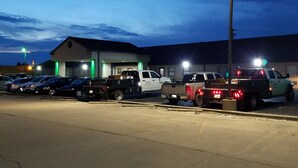 A parking lot with several vehicles, including a white pickup truck and a green utility vehicle. - Briarwood Inn (Fairfield)