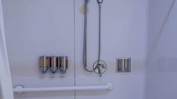 A shower area with a bench, grab bars, and a hand dryer.