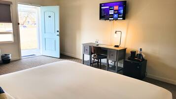 A hotel room with a bed, desk, chair, television, and a coffee maker.