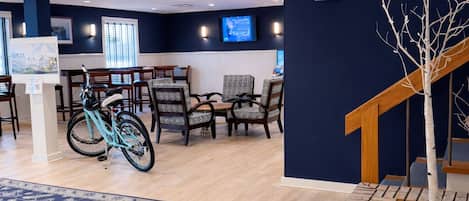Vestíbulo de hotel con una pared azul, una escalera, una jardinera de ladrillo, una alfombra estampada y una bicicleta.