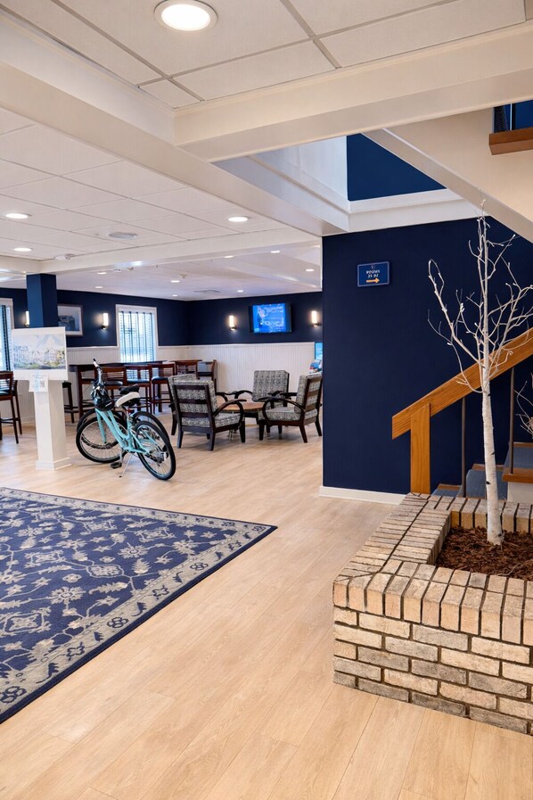 A hotel lobby with a blue wall, a staircase, a brick planter, a patterned rug, and a bicycle. - The Circle Hotel Fairfield (Fairfield)