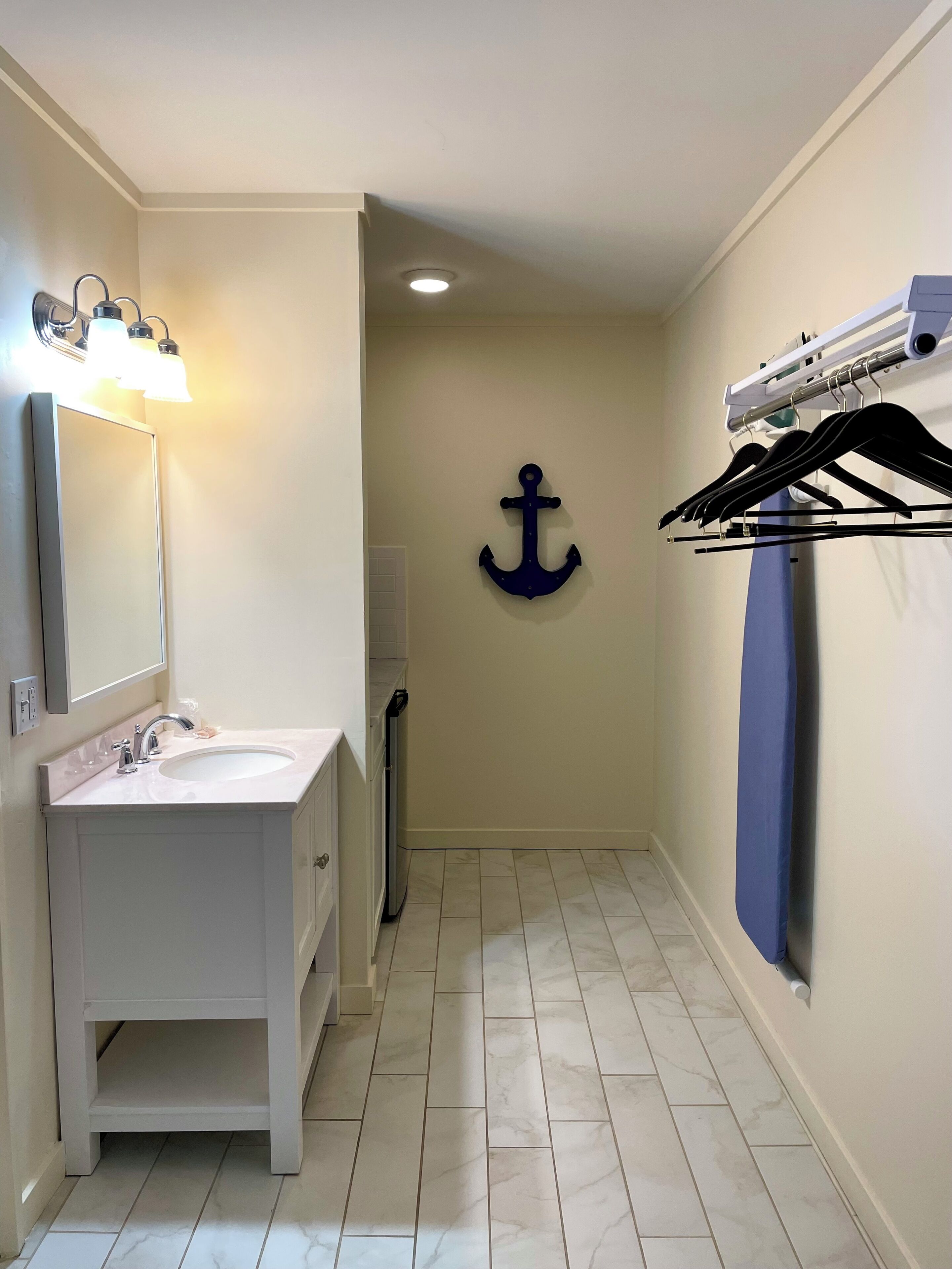A bathroom with a sink, mirror, and an anchor decoration on the wall.