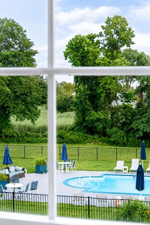A pool area with lounge chairs and umbrellas, surrounded by a fence and greenery. - The Circle Hotel Fairfield (Fairfield)