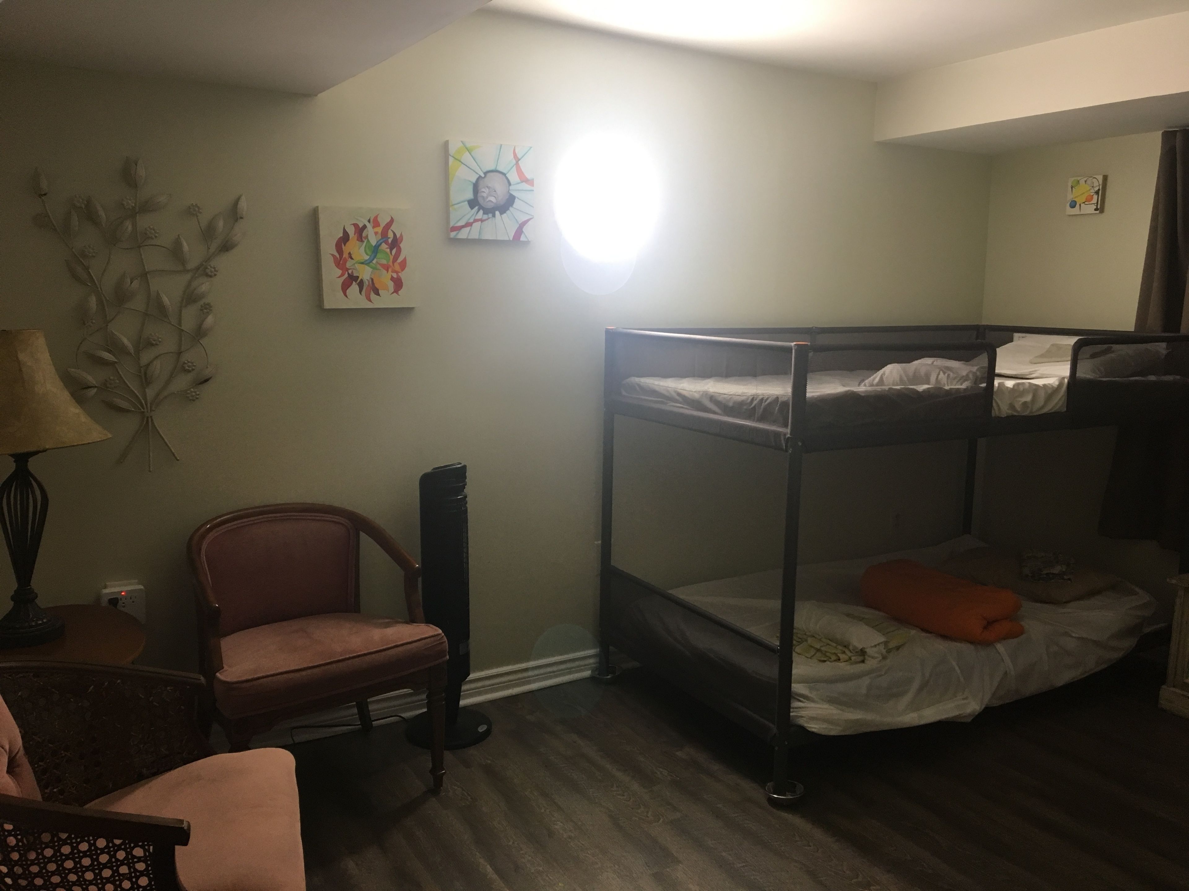 Habitación con literas, una silla, una lámpara y decoración en la pared.