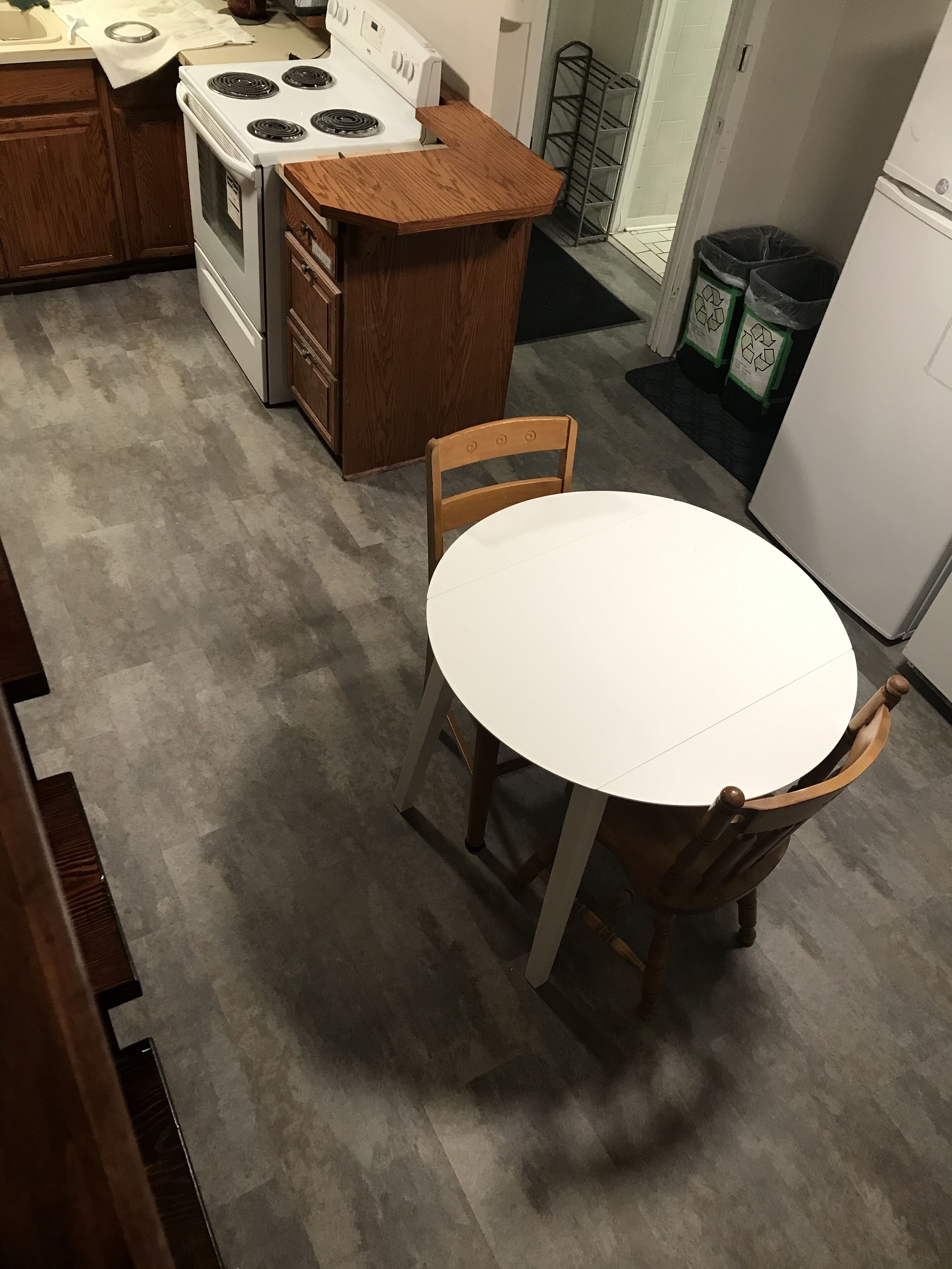 Una cocina con estufa, pileta y encimera de madera. Hay una mesa redonda con sillas.