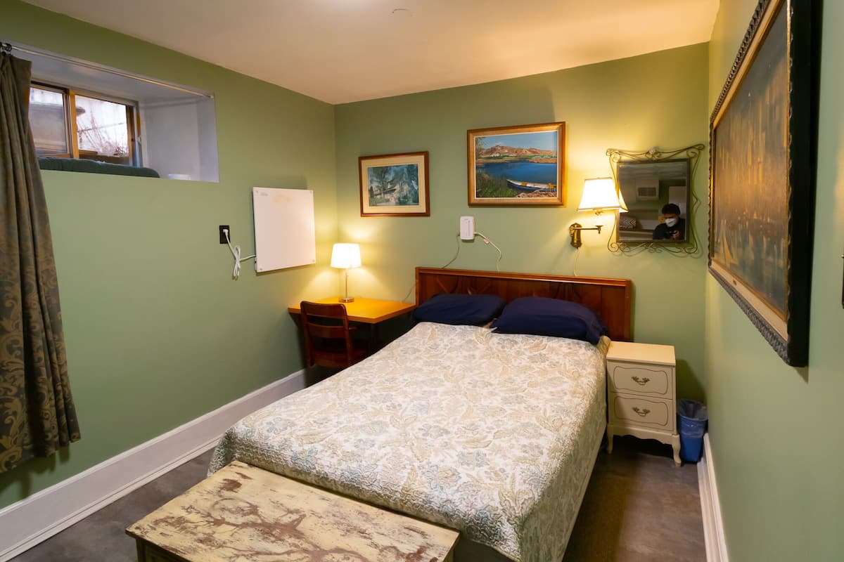 A bedroom with a bed, bedside tables, a lamp, a mirror, and two framed pictures on the wall.