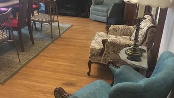 Una sala de estar con chimenea, una mesa de comedor con sillas y una estantería.