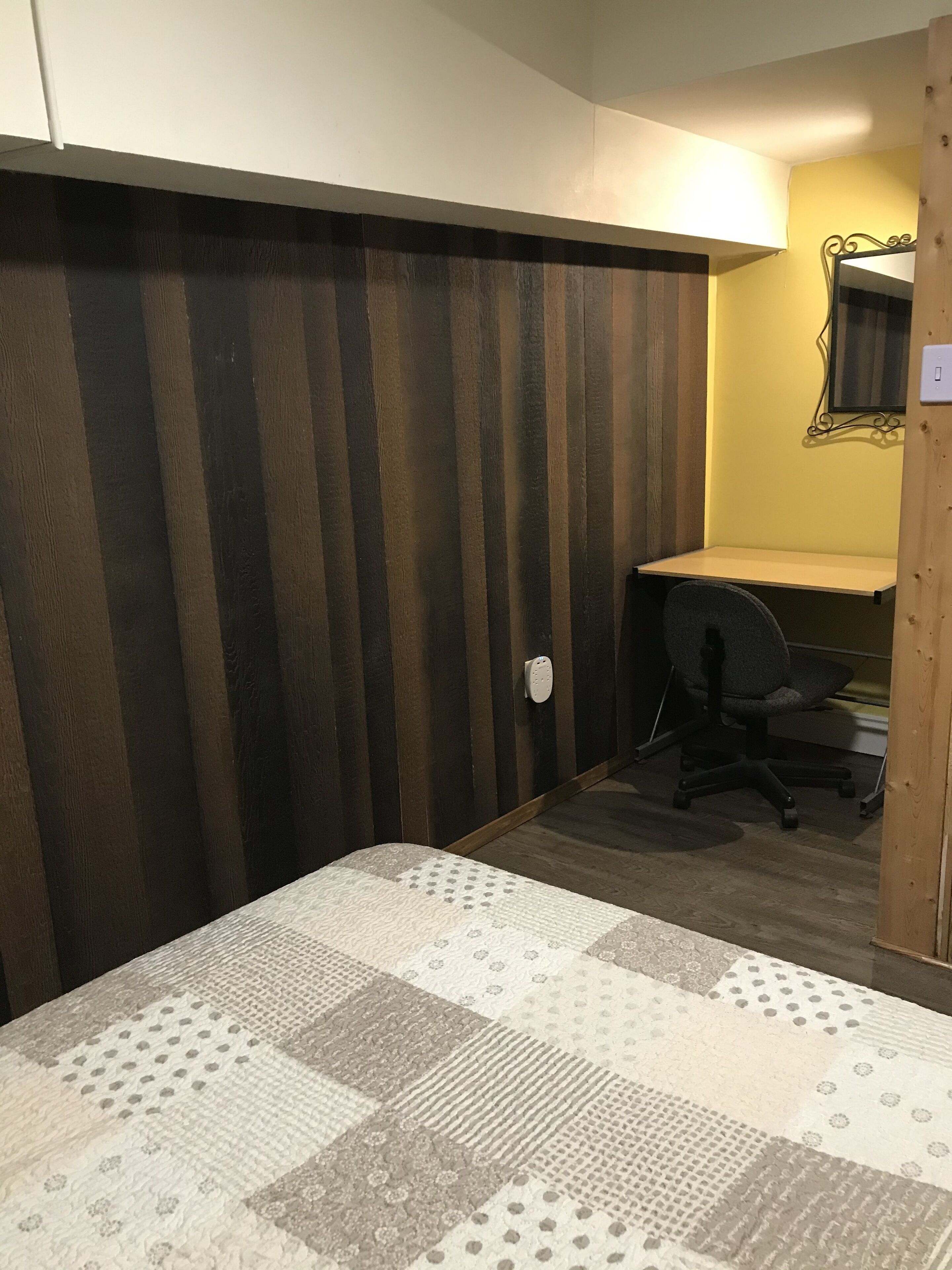 Un dormitorio con cama, escritorio y silla.