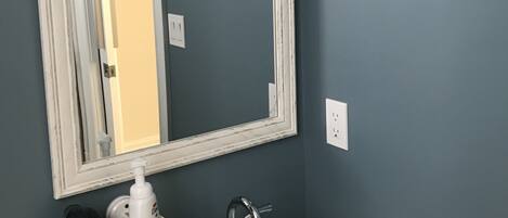 A bathroom with a white sink, a mirror, and a towel hanging on the wall.