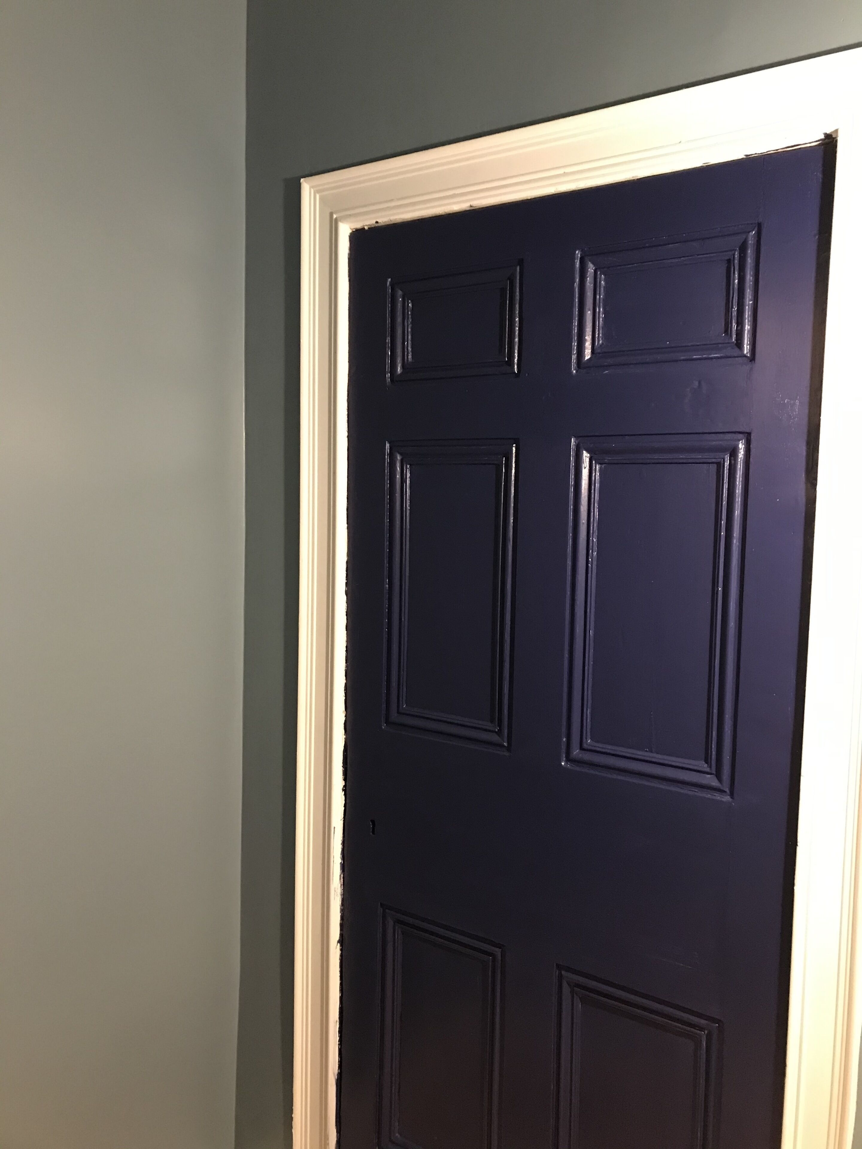 Una puerta azul oscuro con marco blanco.
