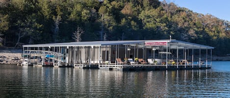 A lakeside cabin with a glass-enclosed deck, docked boats, and a sign for Beaver Lakefront Cabins.
