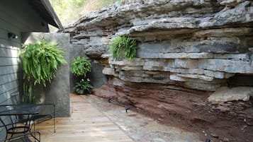 Un patio con muro de piedra, cubierta de madera y dos plantas en macetas.