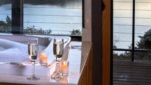 A table with two glasses and a candle, overlooking a lake with a forested hill in the background. - Beaver Lakefront Cabins - Couples Only Getaways (Eureka Springs)