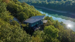 A modern house with a flat roof, large windows, and a deck overlooking a lake. - Beaver Lakefront Cabins - Couples Only Getaways (Eureka Springs)