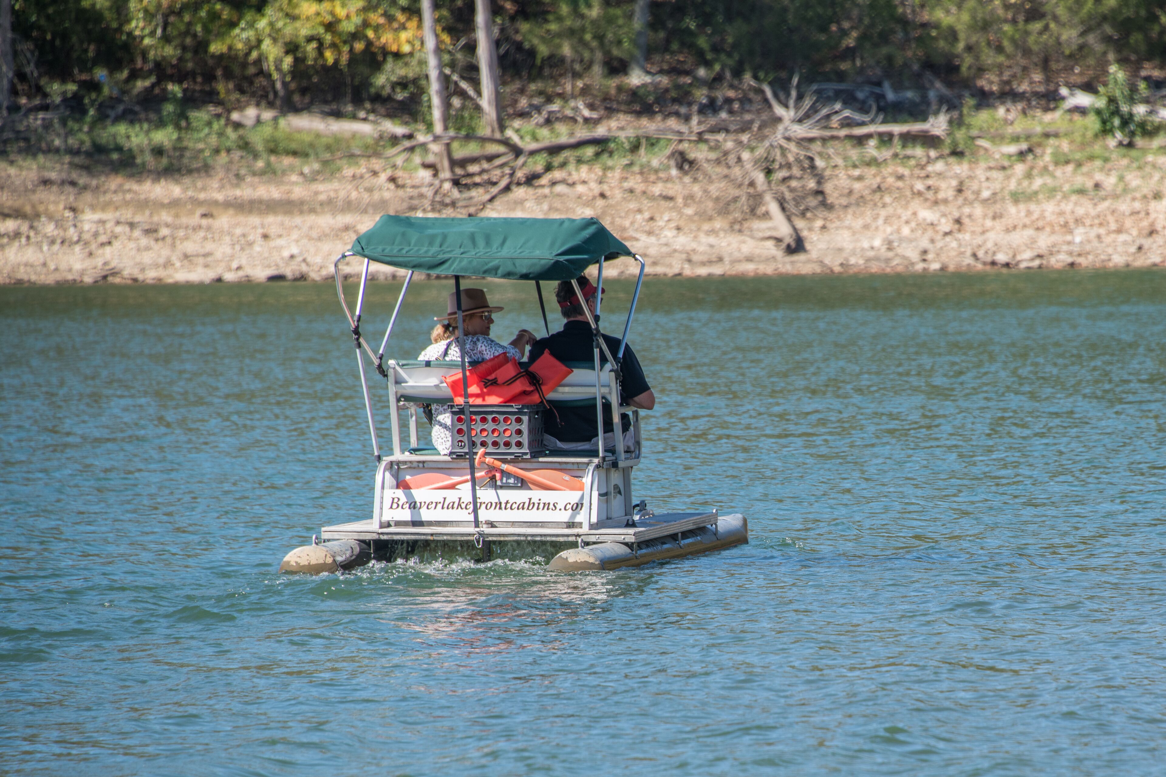 A small boat with a canopy and a life jacket on the back, floating on water.