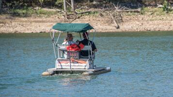 A small boat with a canopy and a life jacket on the back, floating on water.
