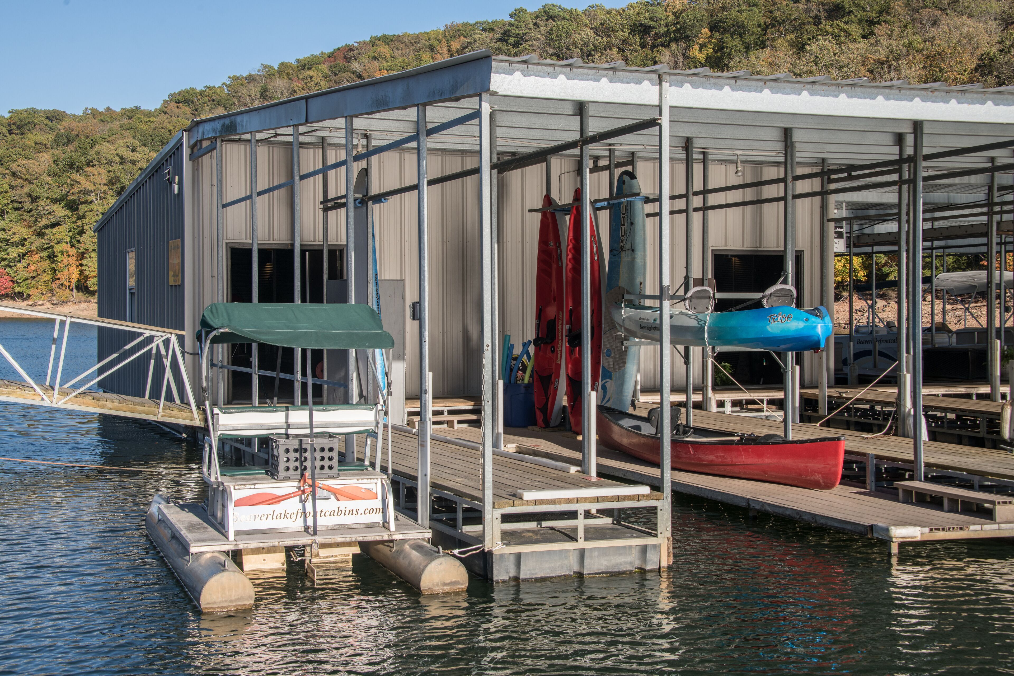 Un quai doté d’un espace de repos abrité, un bateau et un bâtiment avec un toit en métal.