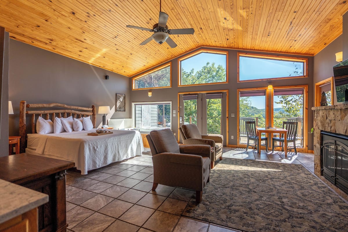 Une pièce spacieuse avec un grand lit, un ventilateur de plafond et une cheminée.