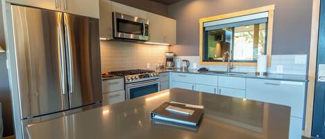 Una cocina moderna con electrodomésticos de acero inoxidable, una isla central y un ventanal sobre el fregadero.