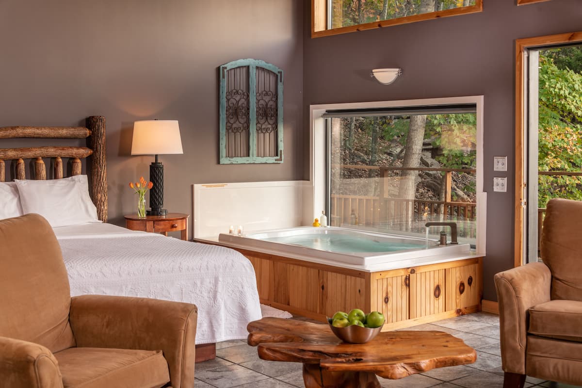 Une chambre avec un grand lit, une baignoire en bois et une vue sur l’extérieur.