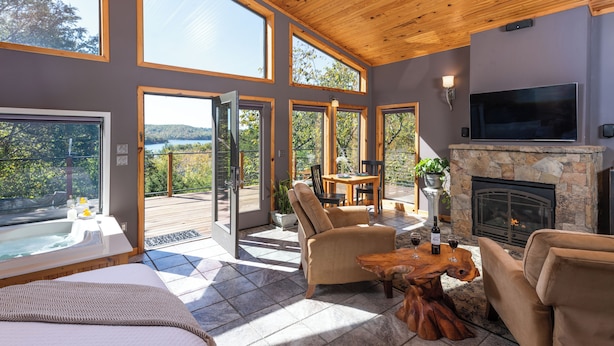 A spacious living area with a fireplace, comfortable seating, and large windows offering views of the outdoors. - Beaver Lakefront Cabins - Couples Only Getaways (Eureka Springs)