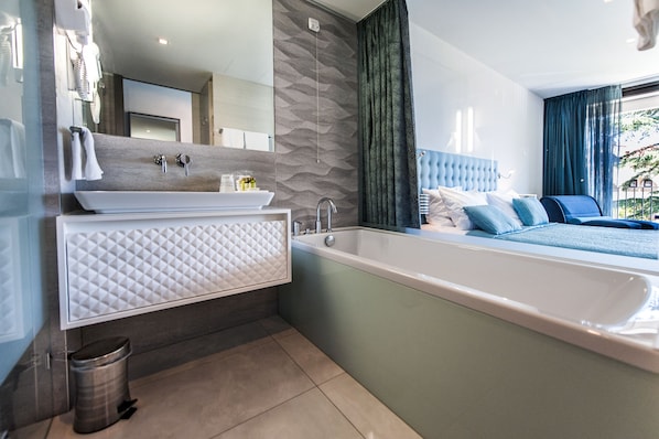 Un baño moderno con una bañera grande, un tocador con espejo y una zona de ducha.