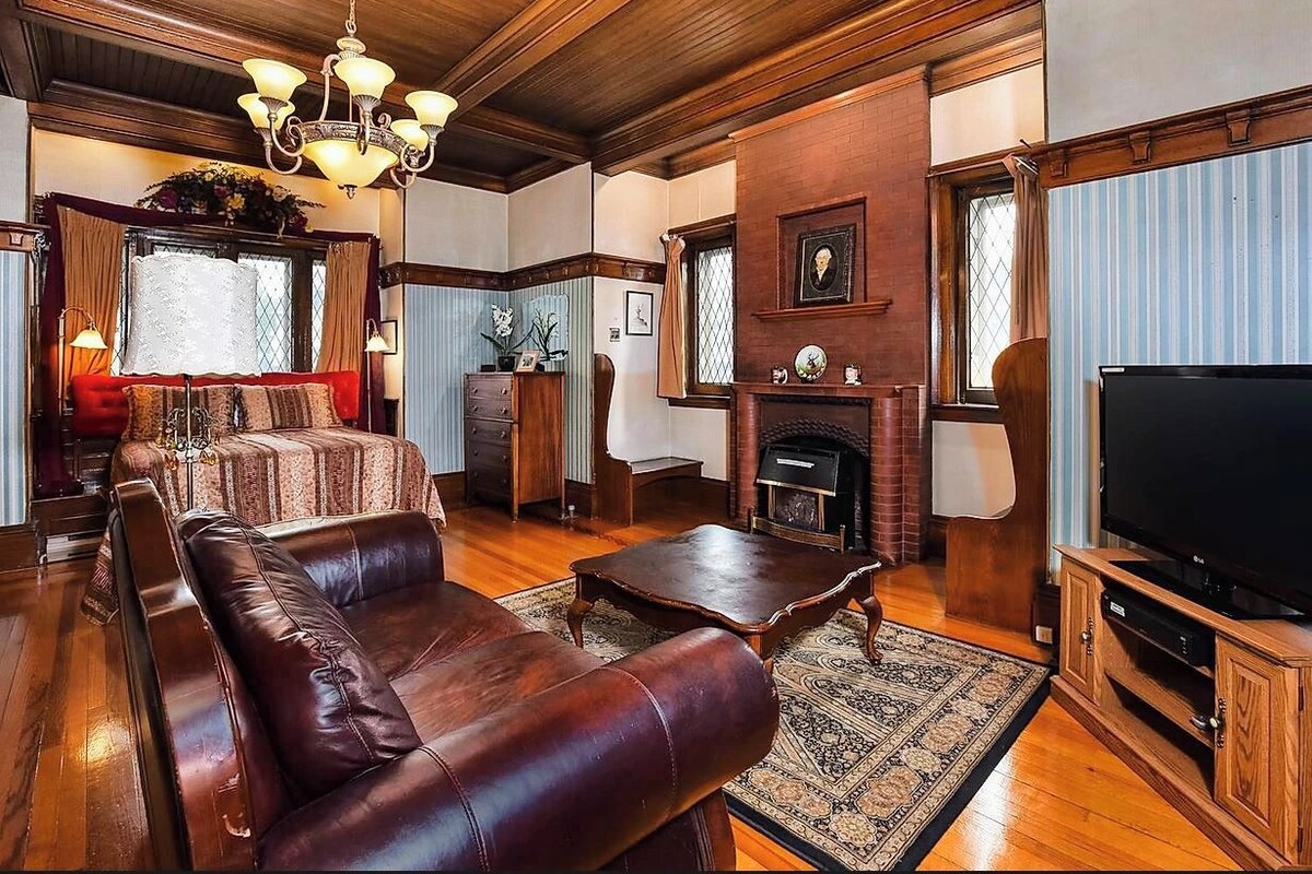 Una sala de estar con un sofá de cuero, una mesa de centro, una chimenea y un televisor.