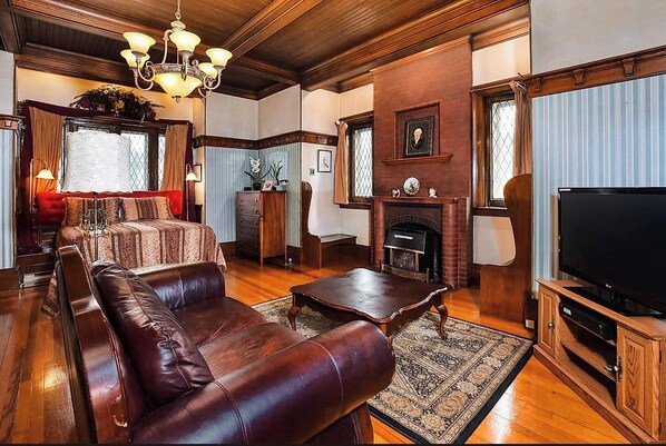 A living room with a leather sofa, a coffee table, a fireplace, and a television.