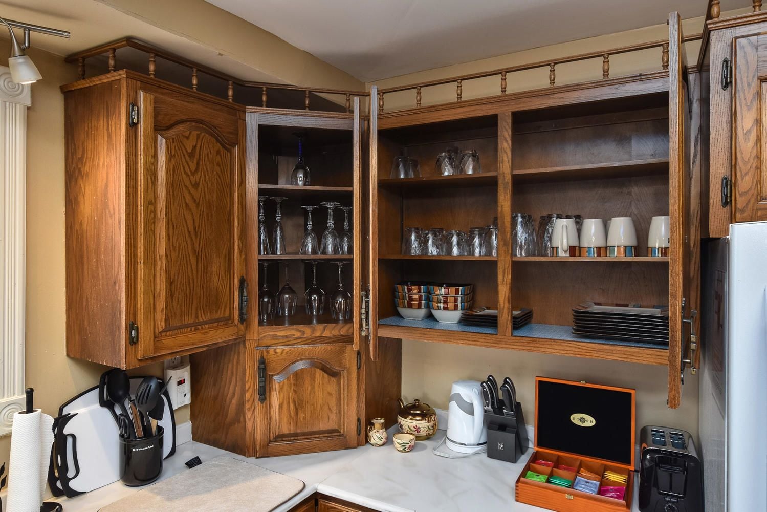 Une cuisine avec des meubles de rangement en bois, un plan de travail sur lequel se trouvent une bouilloire, une machine à café et un grille-pain.